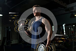 Young man with dumbbells exercising in gym