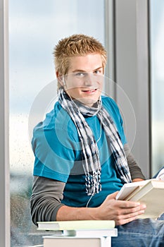 Young man with ear buds and books