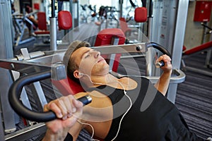 Young man with earphones exercising on gym machine