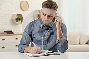 Young man with earphones holding online webinar indoors, view from webcam