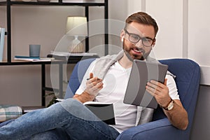 Young man with earphones working on tablet at home