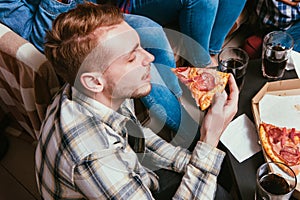 Young man eat pizza at home in friends company