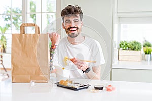 Young man eating asian sushi from home delivery pointing and showing with thumb up to the side with happy face smiling