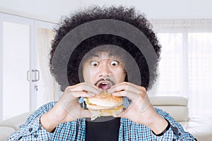 Young man eating a big cheeseburger