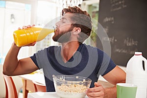 Young Man Eating Breakfast And Drinking Orange Juice