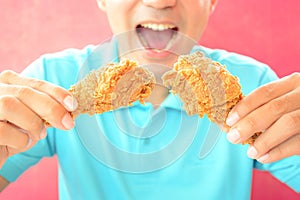 Young man eating deep fried chicken legs or drumsticks