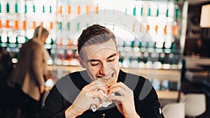 Young man eating fatty hamburger.Craving fast food.Enjoying guilty pleasure,eating junk food.Satisfied expression.Breaking diet