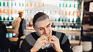 Young man eating fatty hamburger.Craving fast food.Enjoying guilty pleasure,eating junk food.Satisfied expression.Breaking diet