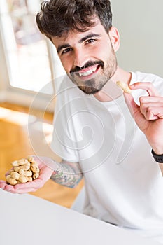 Young man eating peanuts, close up of hand with a bunch of healthy nuts