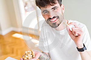 Young man eating peanuts, close up of hand with a bunch of healthy nuts