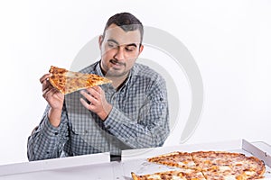 Young man eating pizza with cheese on a white background