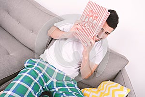 Young man eating popcorn and watching movies