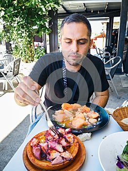 Young man eating Pulpo a la Gallega with potatoes. Galician octopus dishes. Famous dishes from Galicia, Spain