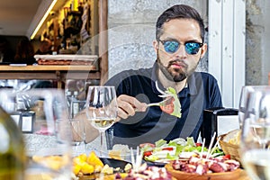 Young man eating vegetable salad and pulpo a la Gallega with potatoes. photo