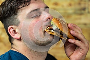 Young man eats delicious appetizing burger