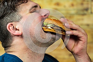 Young man eats delicious appetizing burger