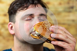 Young man eats delicious appetizing burger