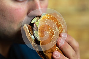 Young man eats delicious appetizing burger