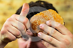 Young man eats delicious appetizing burger