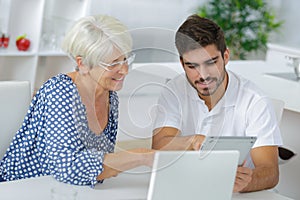 Young man and elderly lady looking at tablet screen