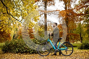 Young man with electric bicycle in the autumn park