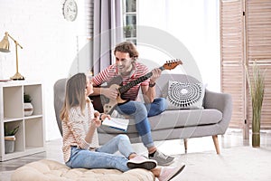Young man with electric guitar and his girlfriend composing song