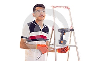 Young man with electric screwdriver and ledder