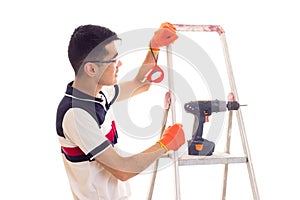 Young man with electric screwdriver and ledder