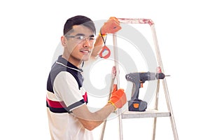 Young man with electric screwdriver and ledder