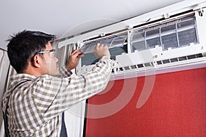 Young man electrician cleaning air conditioning in client house