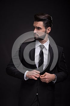 Young man elegant suit buttoning, looking sideways