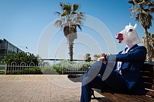 Young man in elegant suit sits on the bench on the city street