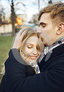 Young man embracing and tenderly kissing his girlfriend, feeling comfortable together.