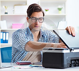 Young man employee working at copying machine in the office