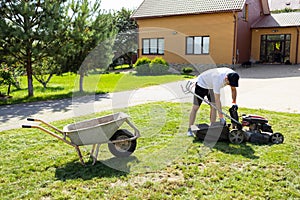 Young man emptying lawnmower grass catcher.