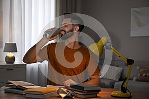 Young man with energy drink studying