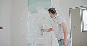 A young man is engaged in a DIY home renovation, focusing on painting a wall. Personal touch in home improvement. Young