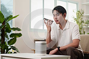 Smart Technology. A man using voice commands with smart speaker at home.