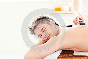 Young man enjoying a back massage with hot stones