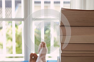 Young man enjoying books near a window. Pleasure of reading books. Relax and holidays.