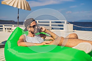 Young man enjoying leisure, lying on the air sofa Lamzac, near the sea