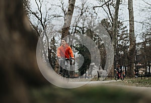 Young man enjoying a leisurely bike ride in a tranquil park on a cloudy day