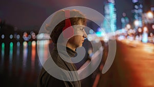 Young Man Enjoying Music with Headphones at Night in the City