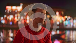 Young Man Enjoying Music with Headphones at Night in the City