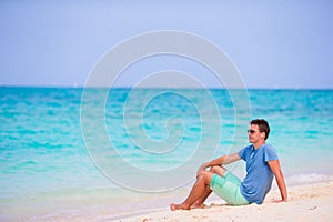 Young man enjoying the music on white sandy beach. Happy tourist relaxing on summer tropical vacation.