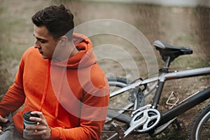 Young man enjoying a peaceful moment with his bicycle in the park on a cloudy day