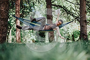 Young man enjoying a playful moment in a hammock in the park