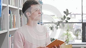 Young man enjoying reading a book at the library