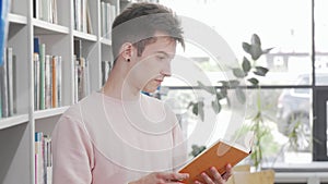 Young man enjoying reading a book at the library