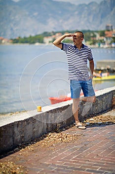 A young man is enjoying the view from the quay during a vacation on the seaside. Vacation, seaside, tourists